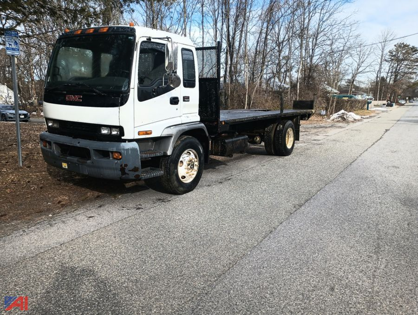 GMC T7500 cab with flatbed truck in a parking lot, white cab, black flatbed, front view