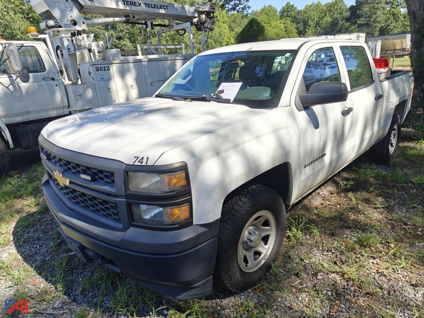 Chevrolet Silverado 1500 pickup truck in light color shown from front-left view with extended cab, outside yard.