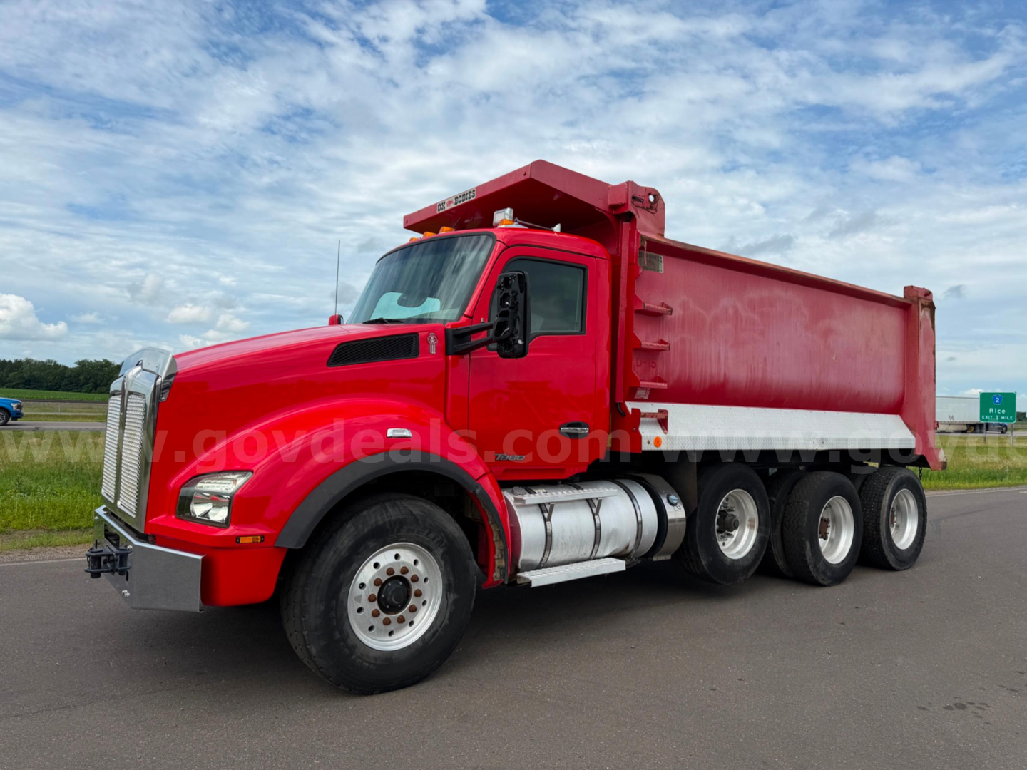 Kenworth T880 dump truck in red with 6x4 wheel arrangement and dual rear axles, side view showing dump bed and cab, no visible text on truck.