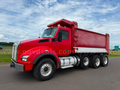 Kenworth T880 dump truck in red with 6x4 wheel arrangement and dual rear axles, side view showing dump bed and cab, no visible text on truck.
