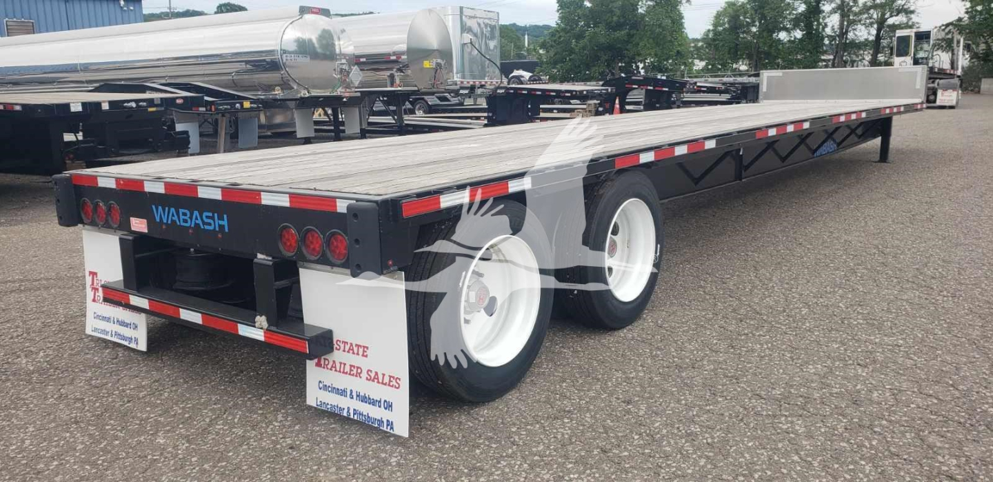 Wabash steel drop deck trailer showing rear and side rails, dual rear axle, and reflective safety strips with WABASH branding on tail.