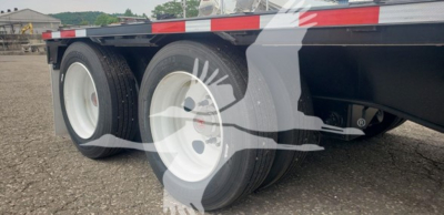 Trailer axle area showing tandem wheels and low deck with white rims; part of a Wabash steel drop-closed tandem trailer.