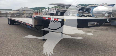 Flatbed trailer with low-profile steel drop deck, black with reflective markings and metal hardware visible in a lot.