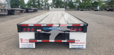Rear view of a used 2024 Wabash steel drop deck trailer showing taillights, white and red reflective tape, WABASH logo, and dealer plates.