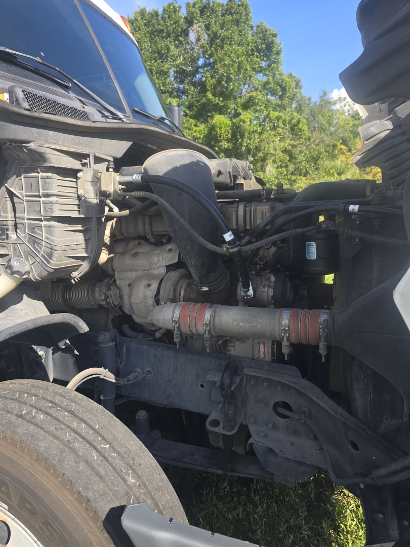 Truck engine bay of a 2017 Freightliner Cascadia CA125DC showing intake hoses, radiator area, and engine components in side view.