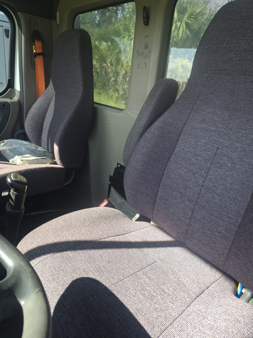 Cab interior of a Freightliner Cascadia CA125DC showing front bucket seats and driver area.