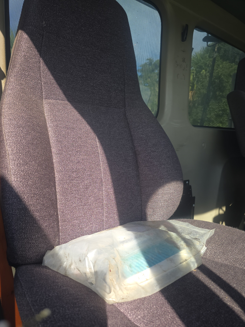 Seat in Freightliner Cascadia CA125DC day cab showing fabric upholstery and a package on the seat.