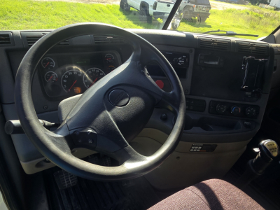 Dashboard and steering wheel of a 2017 Freightliner Cascadia CA125DC cargo truck cab interior view. Visible gauges behind steering wheel, center console with controls, gear shifter on right.