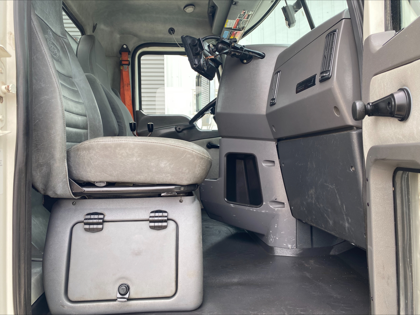 Interior cab of a 2018 Mack GU533 rolloff truck showing driver seat, steering wheel, dashboard, and open door.