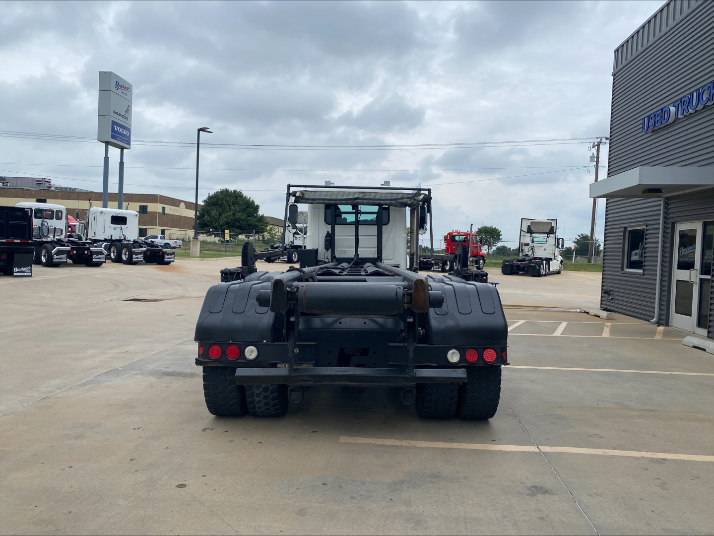 Back view of a 2018 Mack GU533 rolloff truck in a dealership lot showing rear tires, hitch, and taillights.