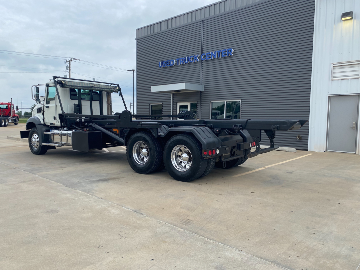 Mack GU533 roll-off truck in serviceable condition showing rear chassis and dual rear wheel assembly with flatbed trailer section.