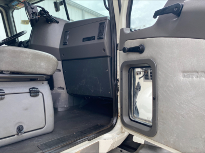 Cab interior of a 2018 Mack GU533 roll-off truck showing front passenger door open and driver seat area with dashboard and center console visible.