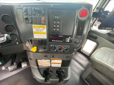 Mack GU533 cab interior showing control panel with various switches, red push button, climate controls, and cup holders.