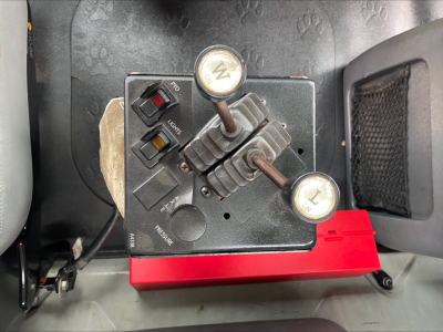 Dash control panel with two levers and switches in a Mack GU533 roll-off truck, showing label text on levers and surrounding dashboard area.