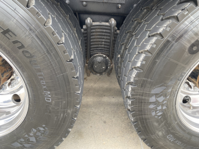 Dual rear wheels and suspension of a Mack GU533 dump truck showing tandem axle with leaf springs and center bogie.
