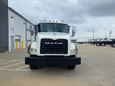 Front view of a white 2018 Mack GU533 roll-off truck showing large black grille with MACK lettering, bumper, and cab mirrors.