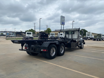 Mack GU533 rear-side view showing heavy-duty truck chassis with multiple axles in a parking lot.