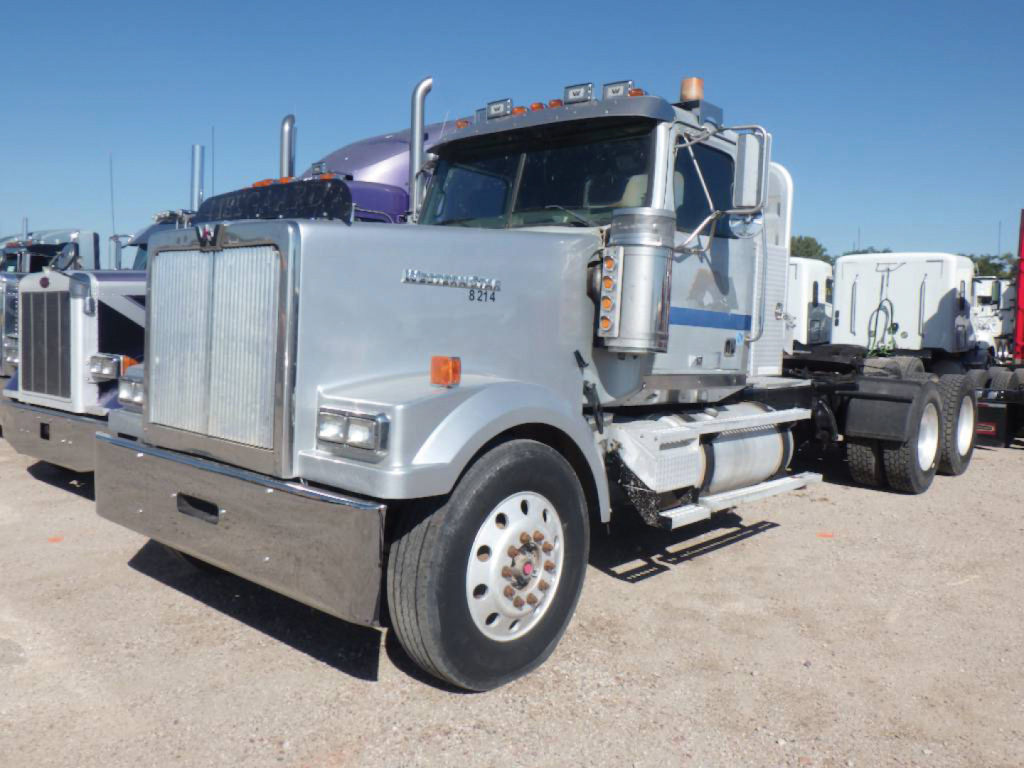 Western Star 4900EX daycab truck front-left view showing chrome grille, dual exhaust stacks, large front bumper, silver/gray paint, and wheel set.
