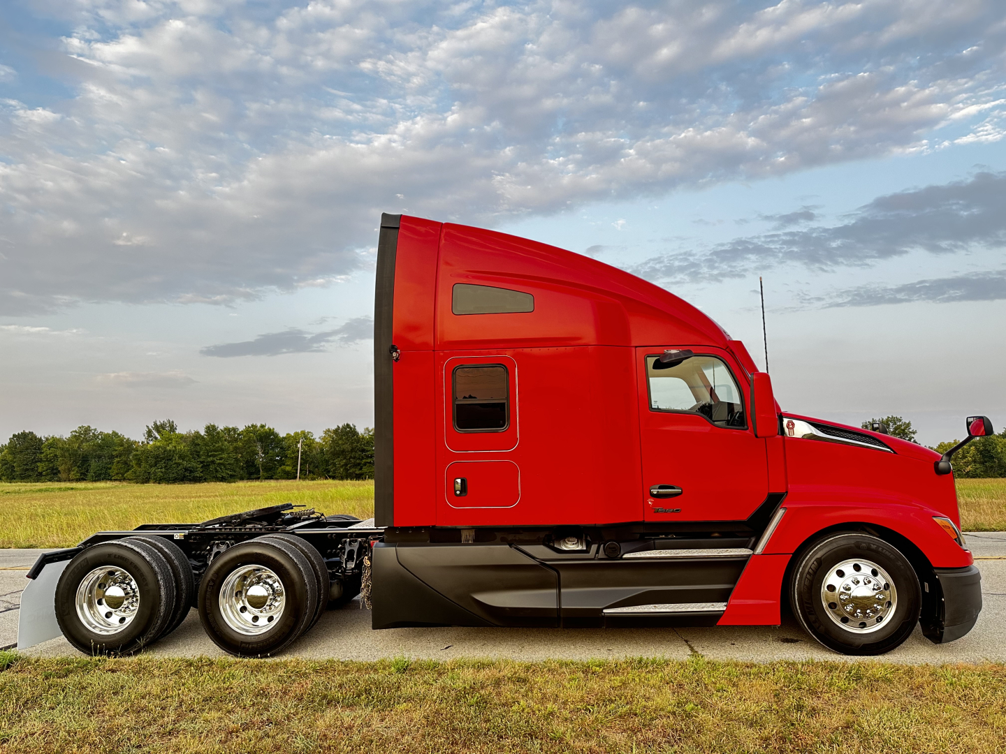 Kenworth T680 tractor in red side profile view showing sleeper cab and rear tandem axles.