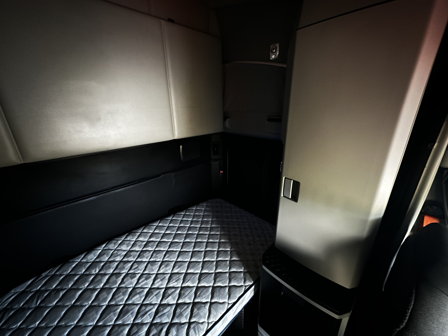 Kenworth T680 sleeper cab interior showing quilted bed mattress and side storage panels.