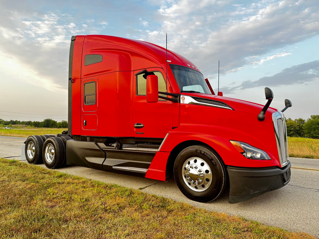 Kenworth T680 tractor in red color showing side view with sleeper cab and dual rear axles.