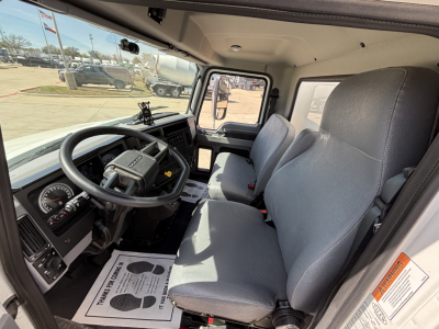 Cab interior of a 2025 Mack MD7 truck showing steering wheel, dashboard, and two gray seats in daylight.