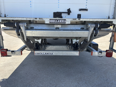 Rear view of a 2025 Mack MD7 cab-over truck trailer hitch with Dhollandia lift system, metal frame, springs, and rear lights.