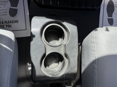 Interior center console with two circular cup holders between front seats of a Mack MD7 truck showing empty cup holders and surrounding plastic trim.