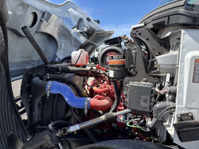 Mack MD7 engine bay with red hoses, blue radiator hose, wiring, and components visible under open hood.