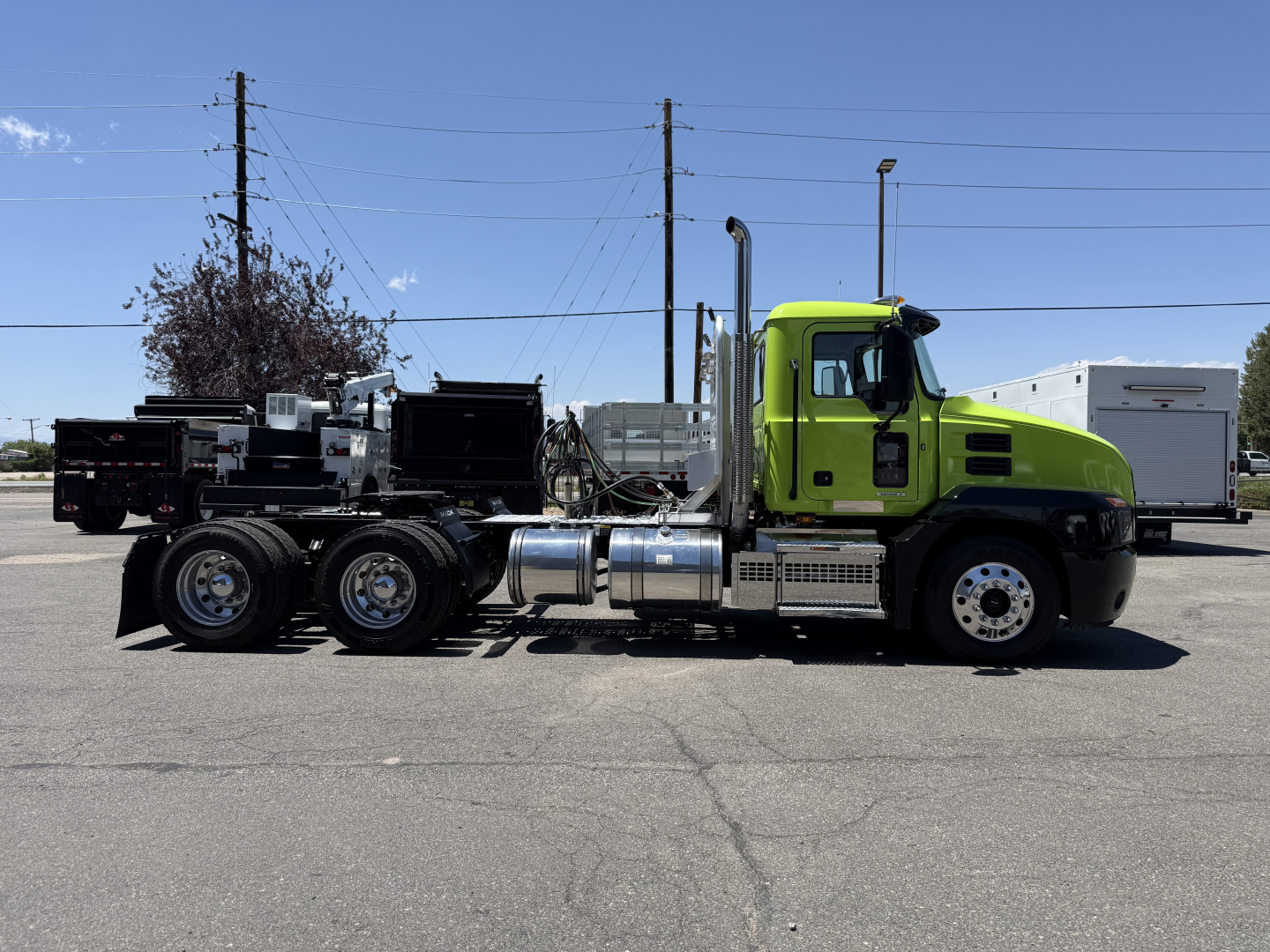 Mack AN64T conventional daycab truck side view showing bright green cab and chrome fuel tanks, dual rear axles, and exhaust stack.