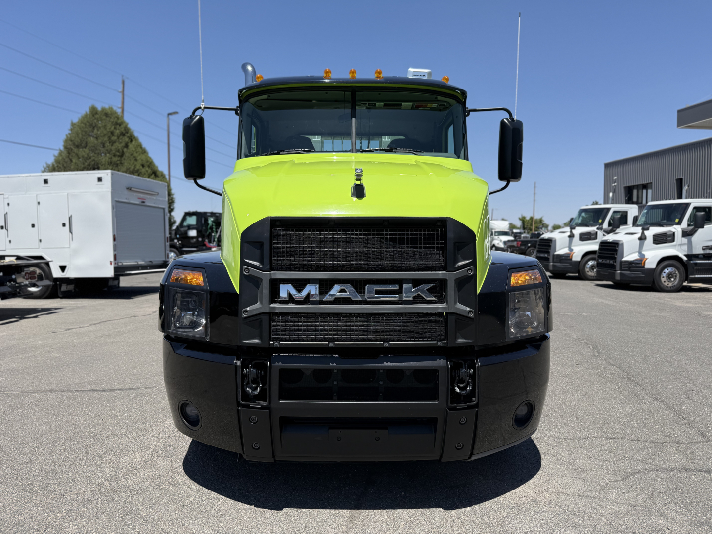 Mack AN64T conventional daycab truck front view. Bright lime green cab with black bumper, large Mack grille, headlights, and side mirrors.