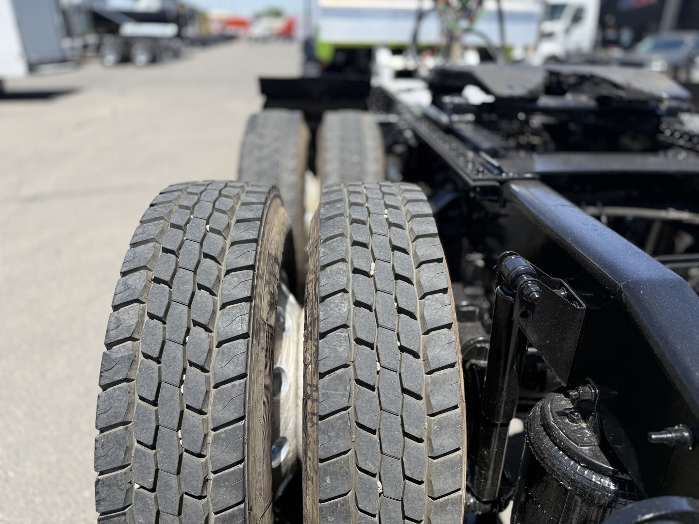 Dual Mack AN64T truck tires on a daycab chassis showing tread patterns and wheel rims.