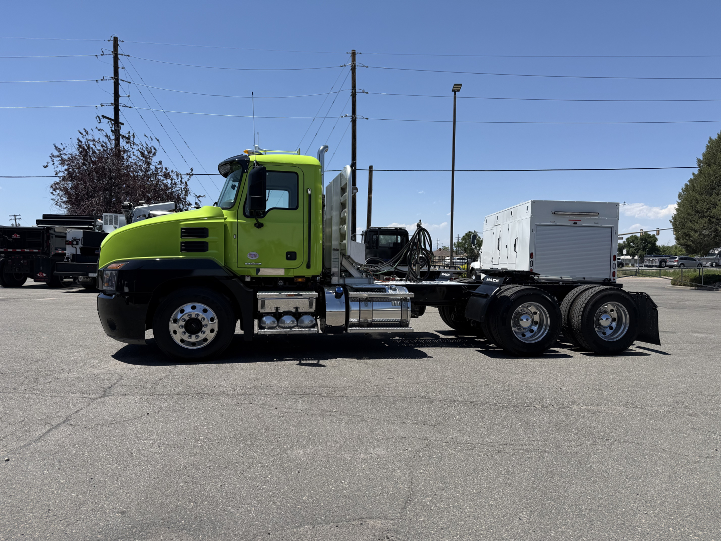 Green Mack AN64T tractor with chassis and fifth wheel, side view showing cab, fuel tanks, exhaust, and rear dual axles.