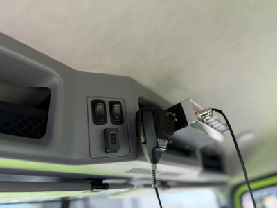 Dashboard area showing a panel with two small square buttons and a toggle, plus a microphone/clip device attached to a black cable.