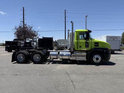Mack AN64T conventional daycab truck side view showing bright green cab and chrome fuel tanks, dual rear axles, and exhaust stack.