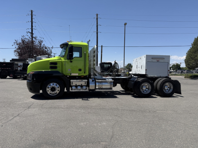 Green Mack AN64T tractor with chassis and fifth wheel, side view showing cab, fuel tanks, exhaust, and rear dual axles.