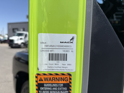 Mack AN64T truck VIN label on bright yellow frame showing VIN 1M1AN4GY6SM048803 and gross weight 16380 lb, bar code, and factory weight data plus a warning label.