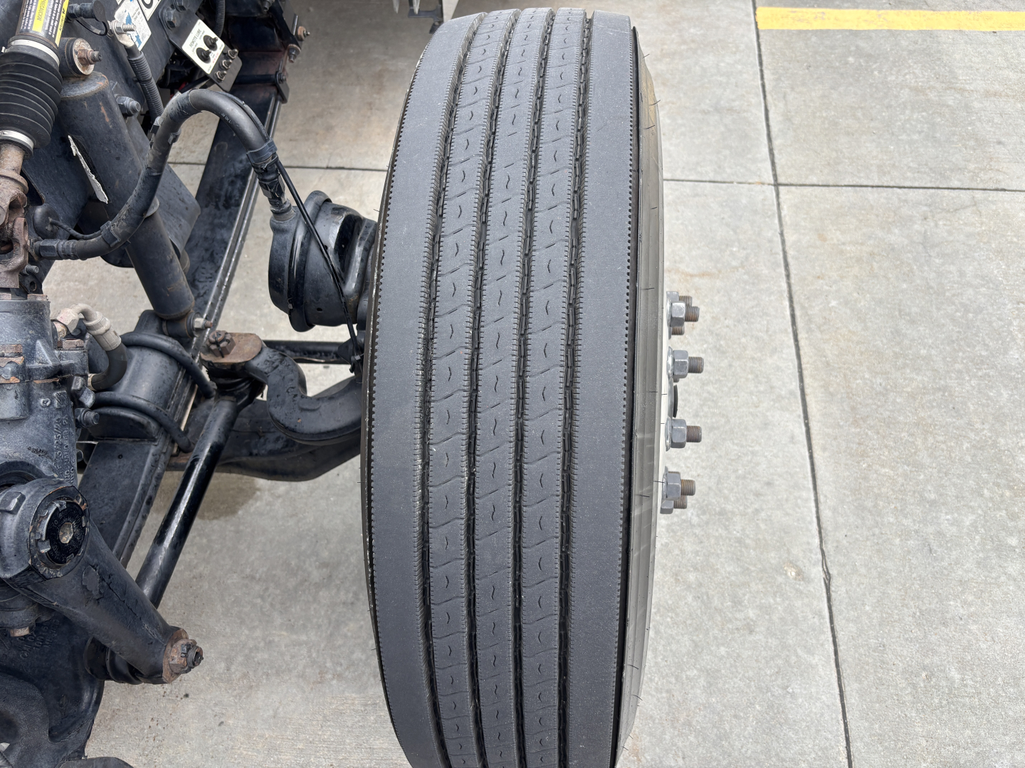 Truck wheel and suspension components visible with a single tall tire and bolts, part of a Peterbilt 389 chassis.