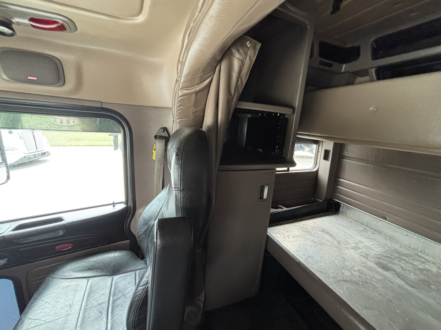 Peterbilt 389 truck cabin interior showing sleeper bunk and storage cabinet with shelf and monitor compartment.
