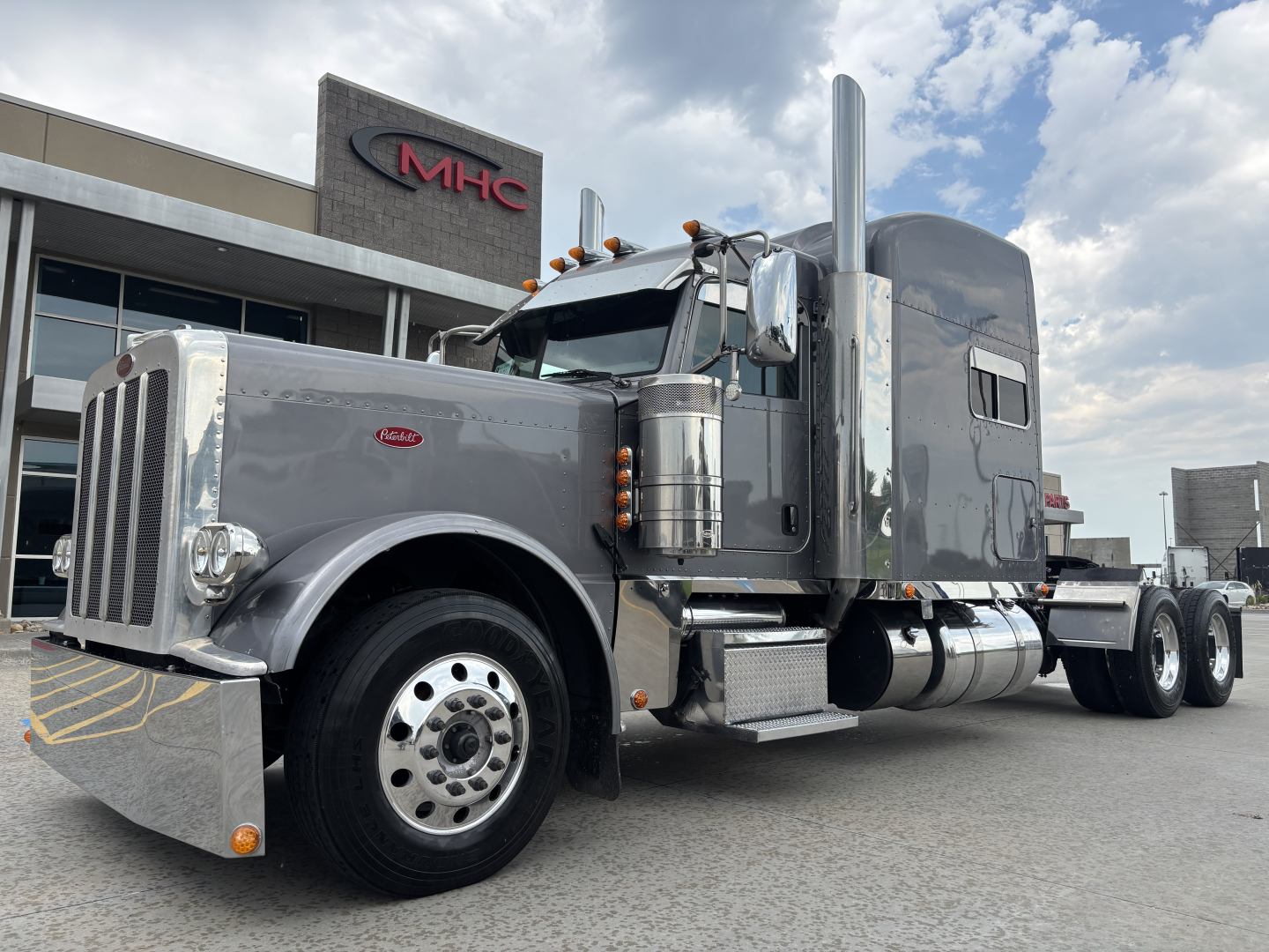 Peterbilt 389 conventional sleeper tractor truck side view showing chrome front bumper, large exhaust stacks, aluminum fuel tanks, and sleeper cab.
