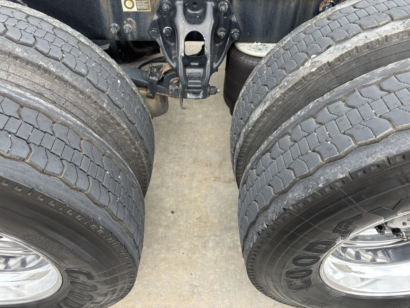 Peterbilt 389 dual rear tires and fifth wheel area showing suspension and drive axles with inspection tag.