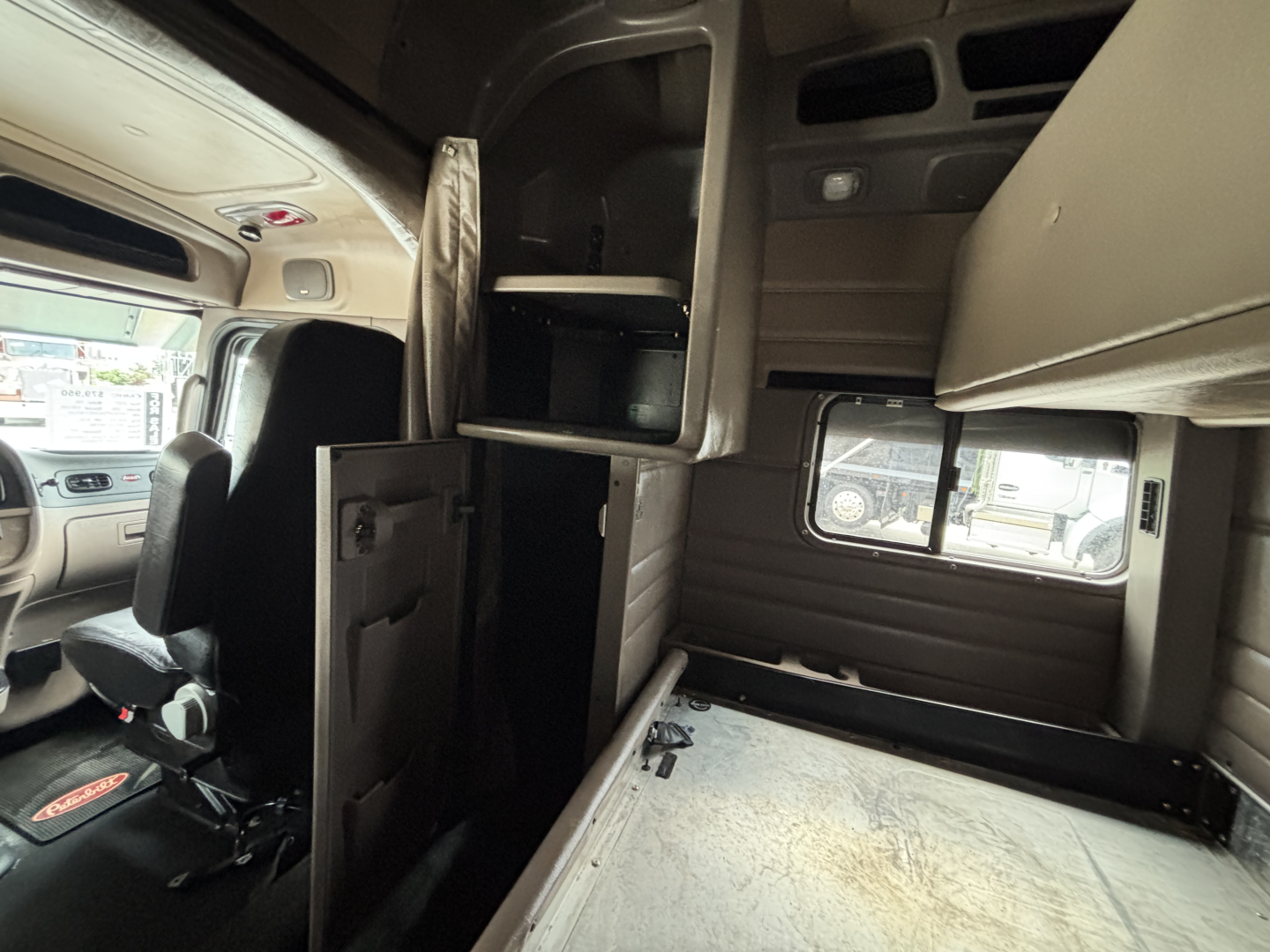 Interior of a 2021 Peterbilt 389 sleeper cab showing bunk area, side window, and storage compartments with overhead panels.