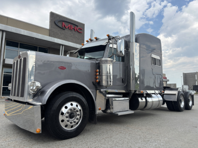 Peterbilt 389 conventional sleeper tractor truck side view showing chrome front bumper, large exhaust stacks, aluminum fuel tanks, and sleeper cab.