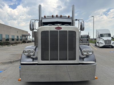 Peterbilt 389 front view showing large grille, dual round headlights, tall exhaust stacks, and chrome bumper with amber marker lights.