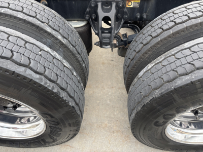 Dual rear tractor tires and rear axle undercarriage of a 2021 Peterbilt 389 truck showing the dual wheel configuration and suspension components.