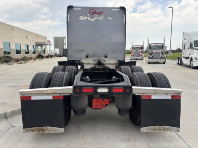 Peterbilt 389 tractor rear view showing dual rear axles, mud flaps, and fifth wheel with red taillight assembly.