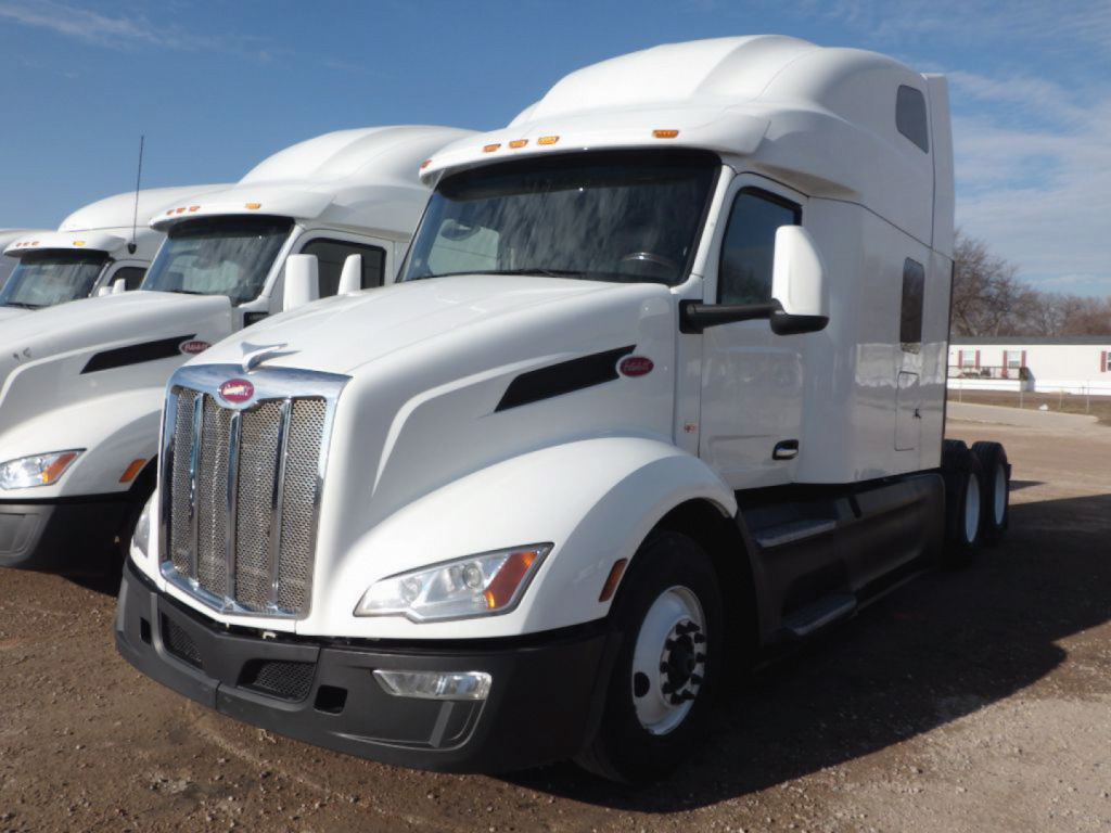 Peterbilt 579 conventional sleeper truck in white, front three-quarter view, with chrome grille and large sleeper cab