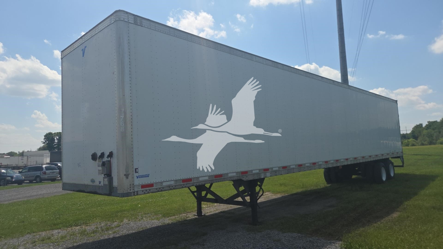 Trailer side view showing large white bird graphic on gray Vanguard trailer with towing hitch and dual rear wheels.
