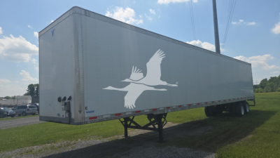 Trailer side view showing large white bird graphic on gray Vanguard trailer with towing hitch and dual rear wheels.