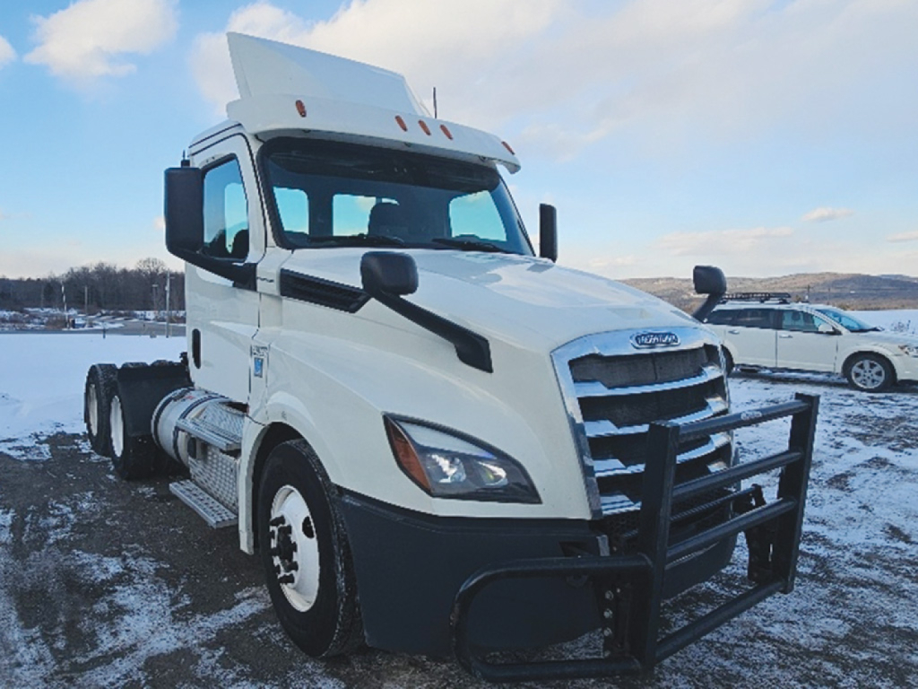 Front left view of a white Freightliner Cascadia126 daycab truck showing grille guard and dual exhaust with snow background.